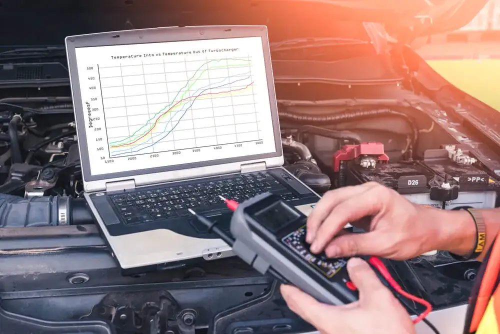 Mechanik samochodowy podłączający komputer diagnostyczny do auta